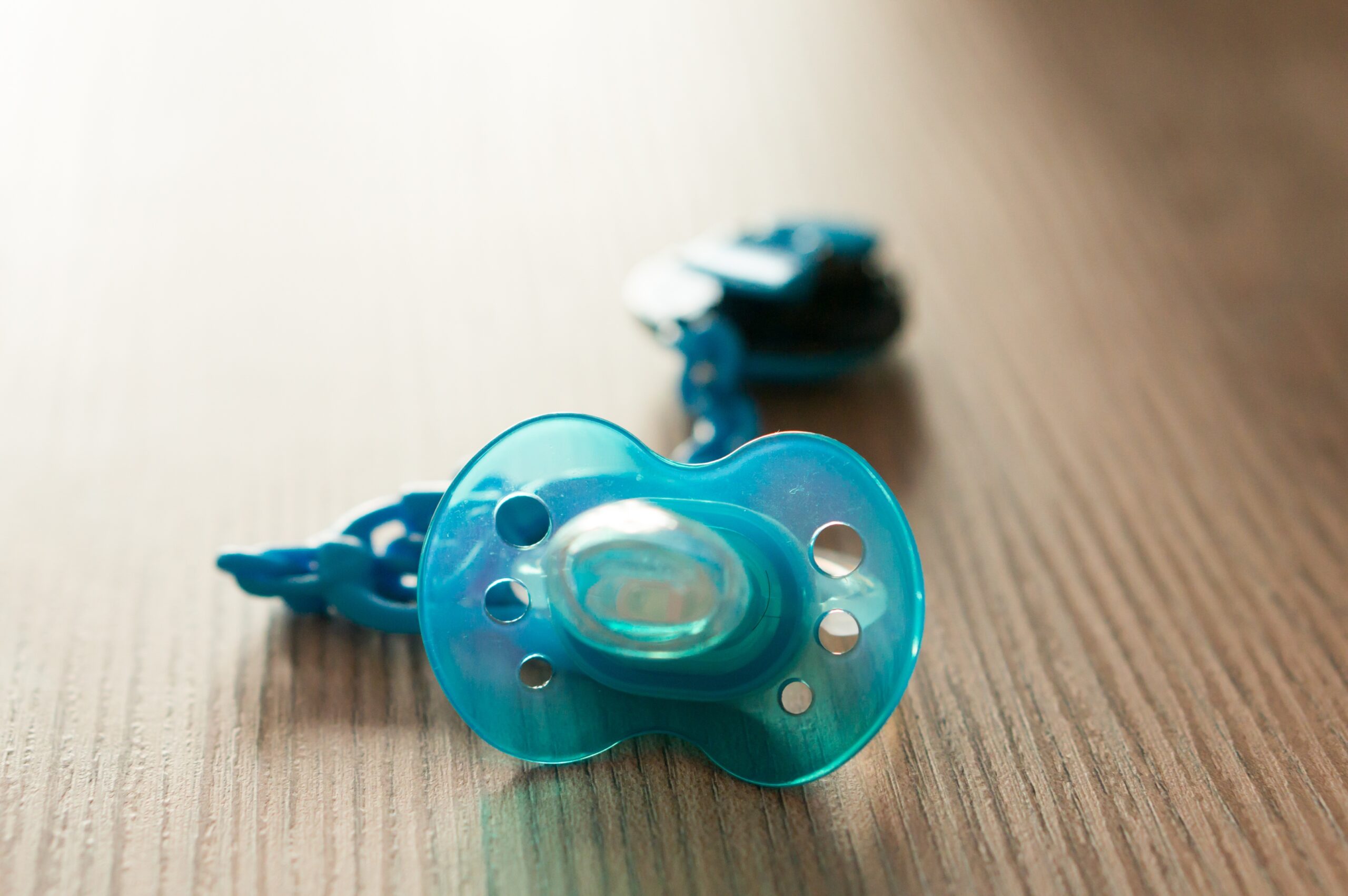 closeup shot of a blue pacifier on a table with a blurred background