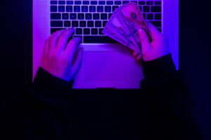 money in male hands on the background of a laptop keyboard in neon lighting.
