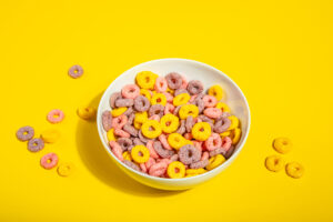bowl of colorful cereal corn rings on yellow table. breakfast concept.