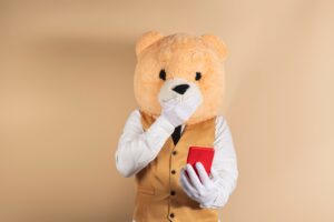 man wearing a teddy bear mask and a professional suit holding a red telephone in the studio