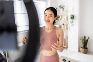 professional female fitness trainer streaming an online training class from home.