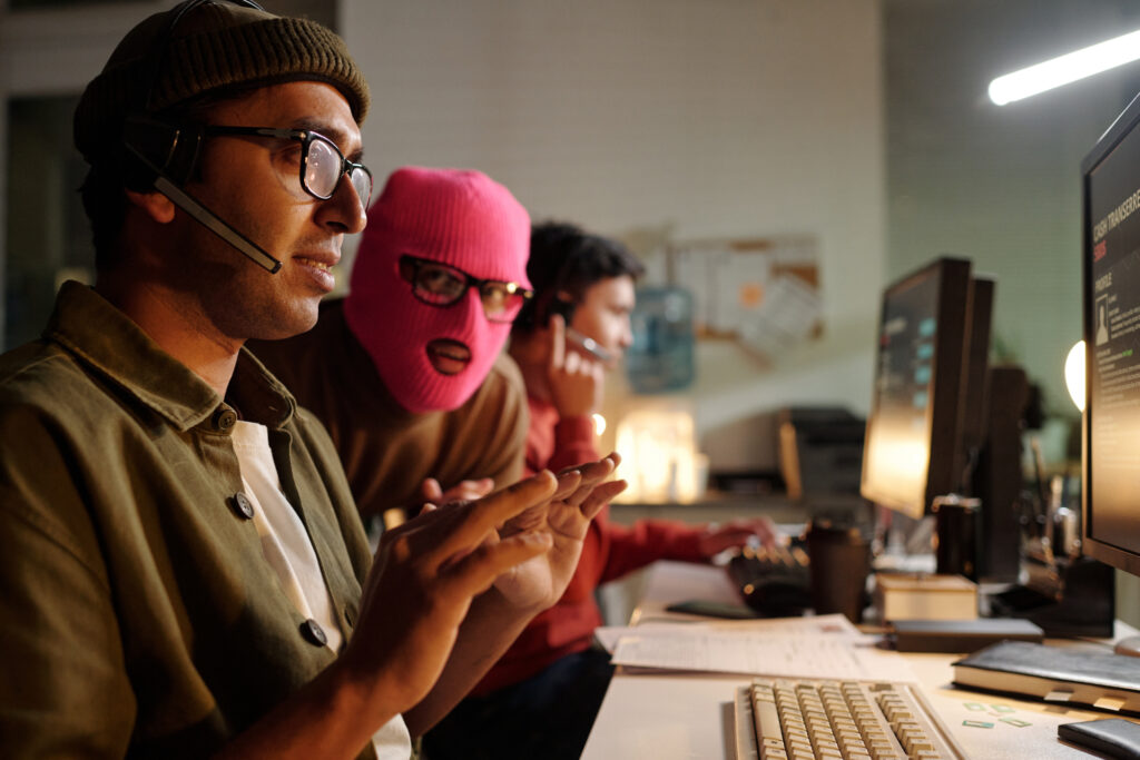 young adult south asian man operating scam call center with masked accomplice