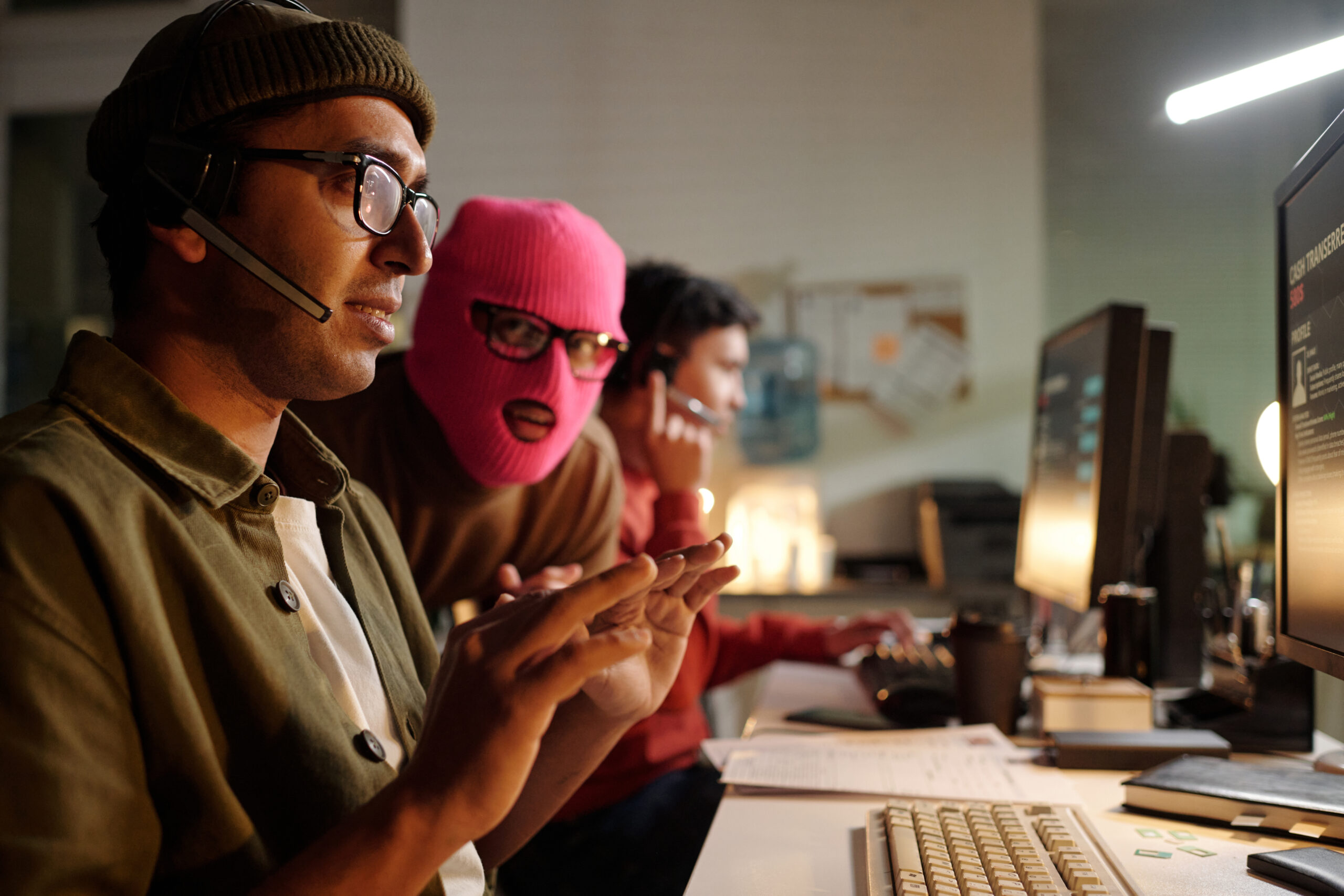 young adult south asian man operating scam call center with masked accomplice