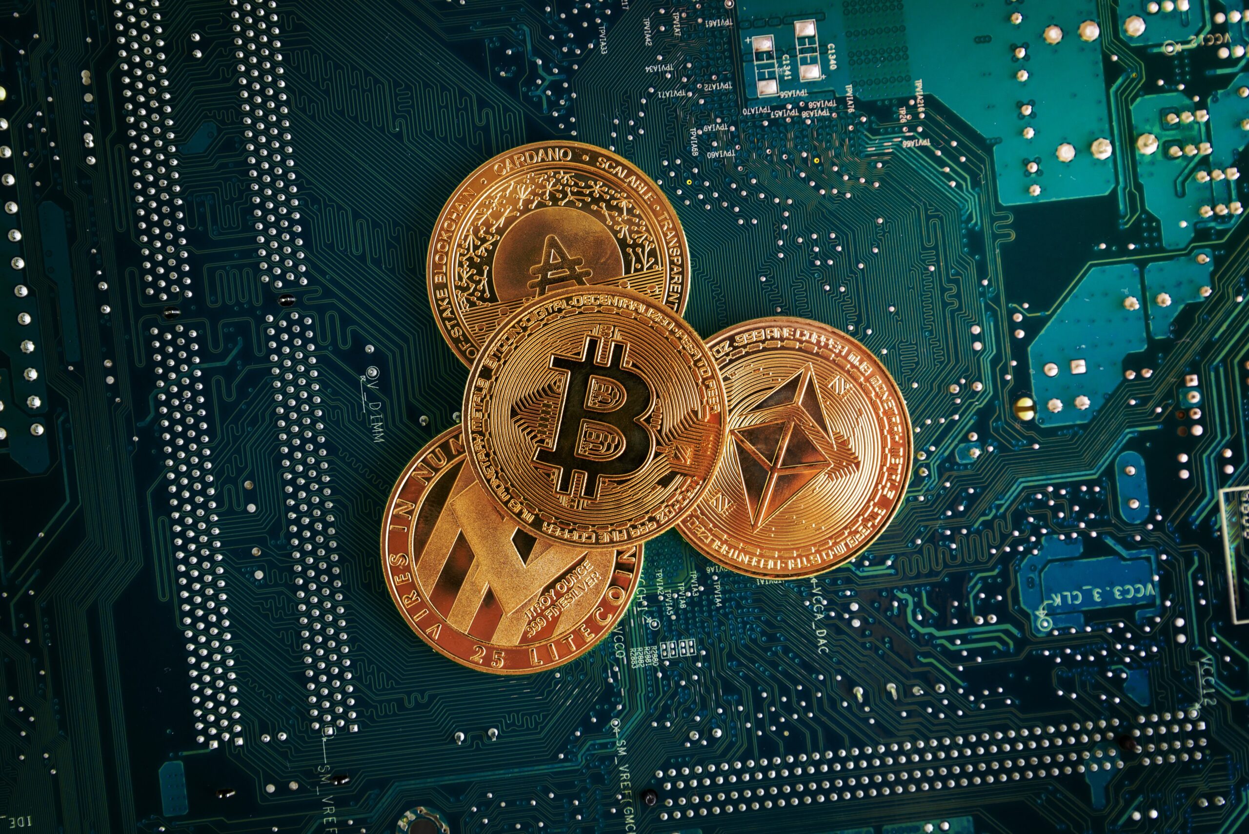 closeup of bitcoin, ethereum, litecoin and cardano coins on the electronic circuit board.