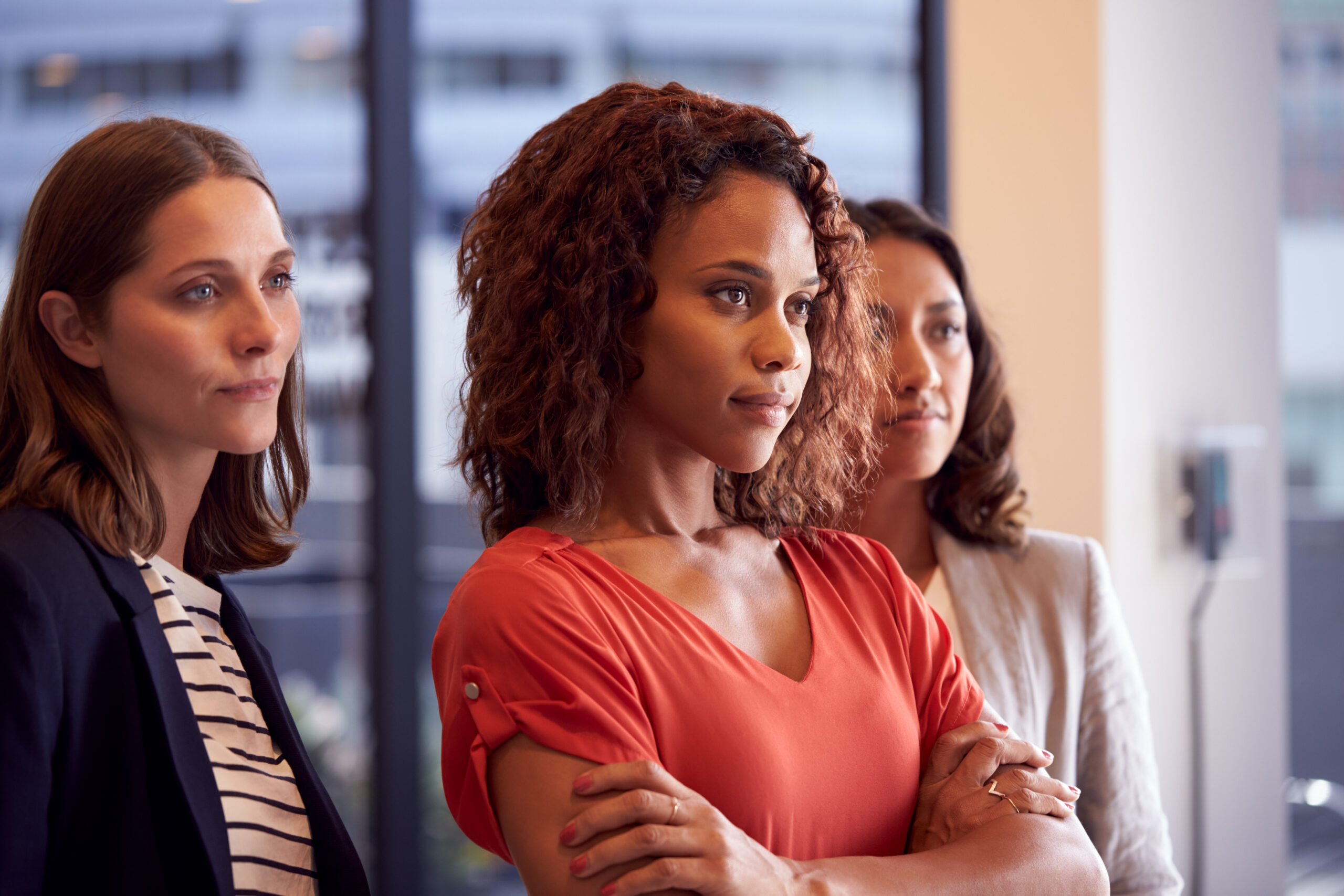 three businesswomen standing in modern open plan office together
