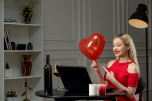 virtual love cute blonde girl in red dress on distance date with wine holding red balloon